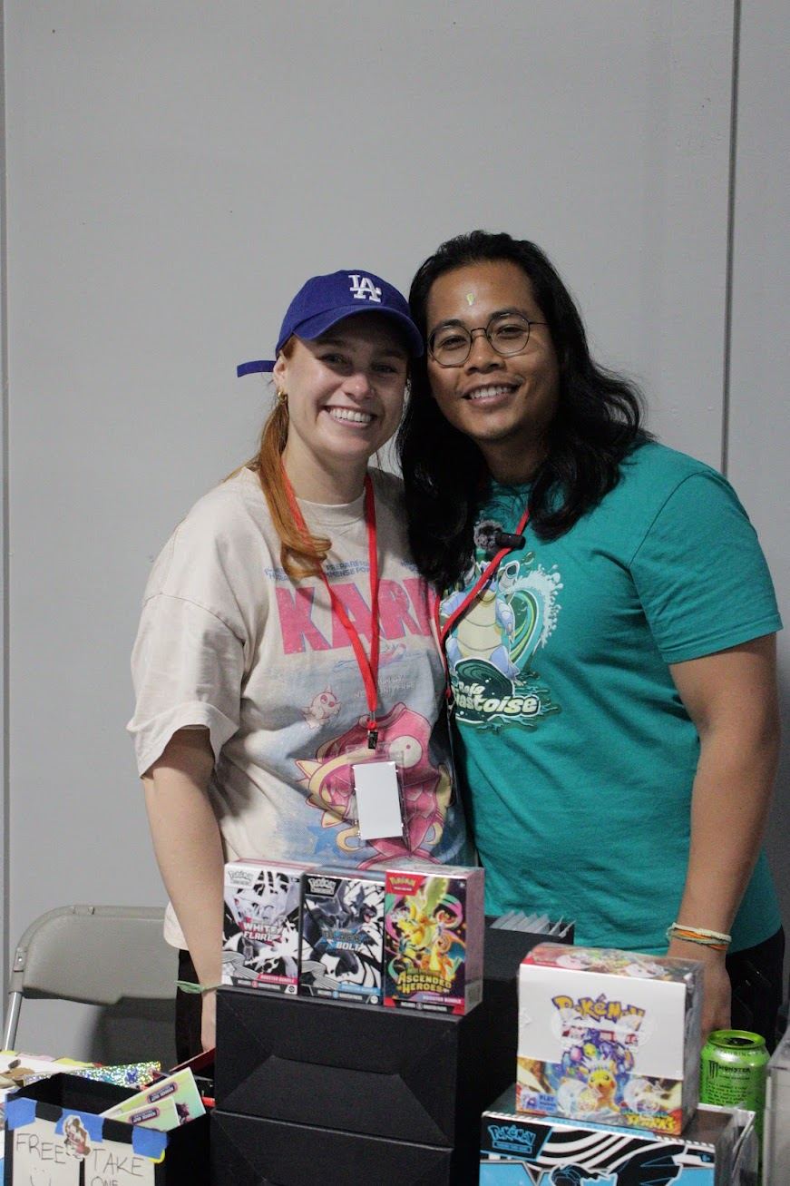 Two vendors smiling behind a table of sealed product